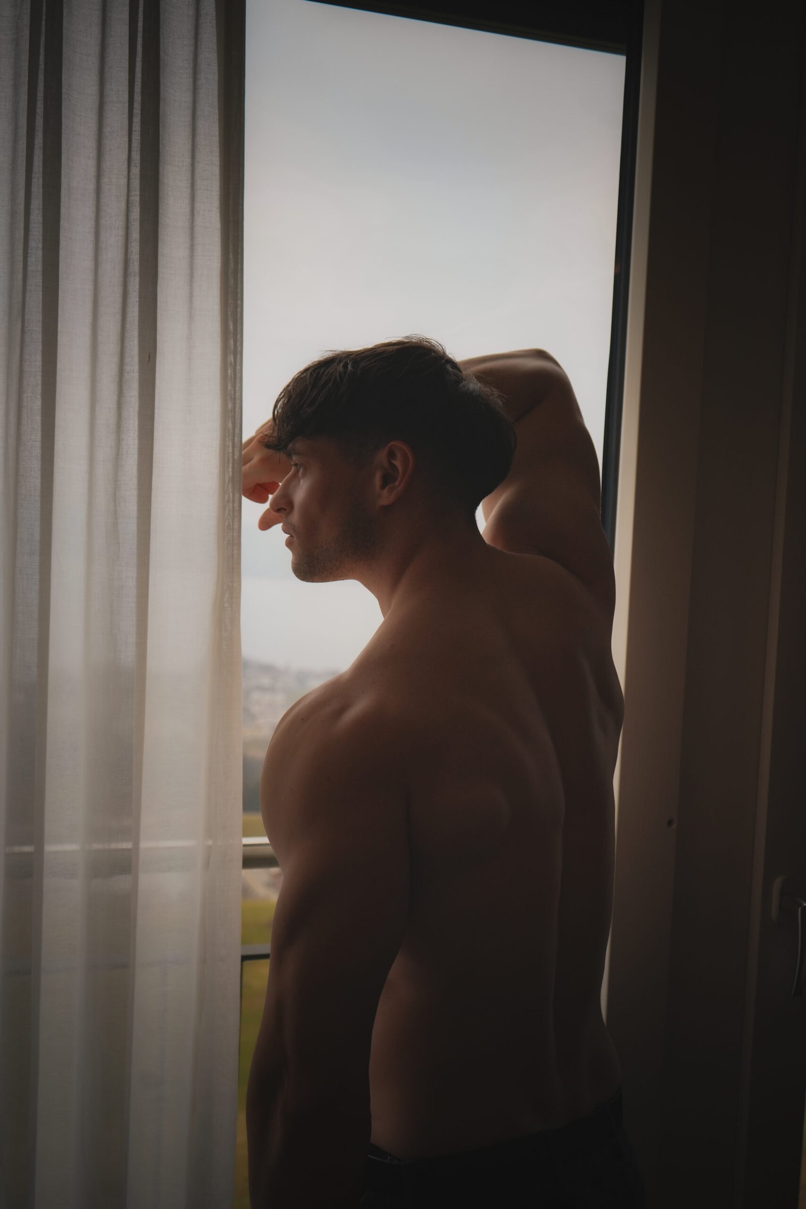 Callboy lehnt sich an Fenster und schaut raus